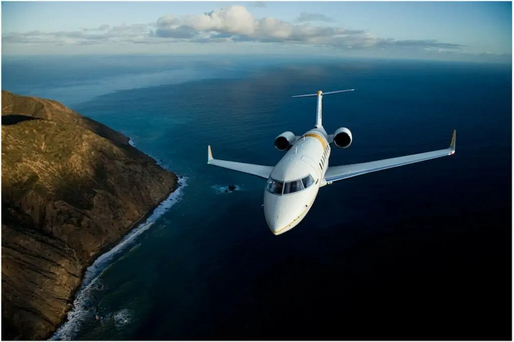 Bombardier Challenger 650 Außenaufnahme aus der Luft, die über Meer und Berge fliegt