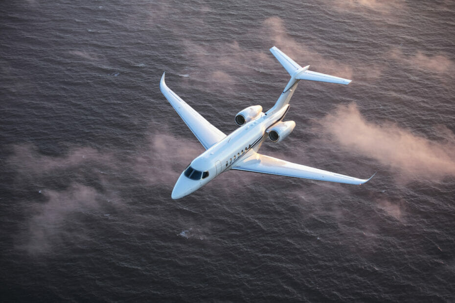 Cessna Citation Longitude Exterieur wit vliegen boven de zee en de wolken