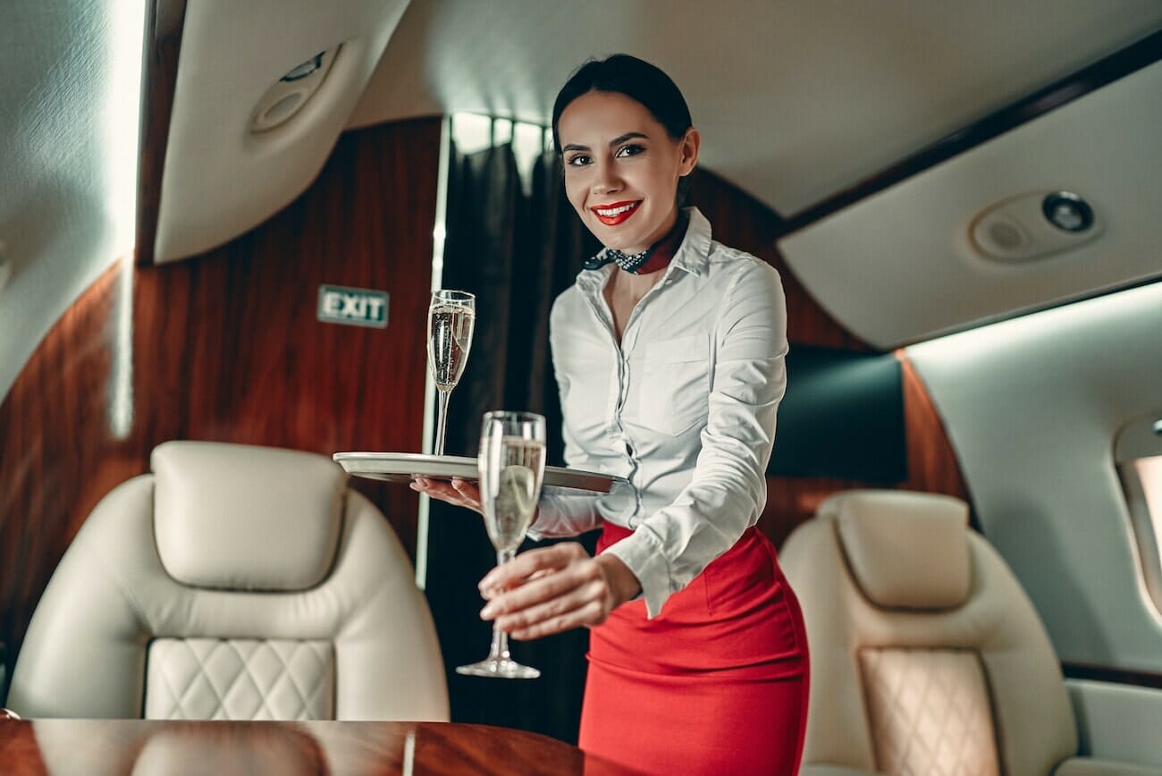 Частен самолет чартърен въздушен стюард, поднасящ шампанско на частен самолет