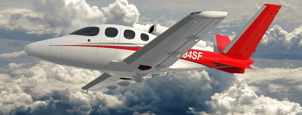 Side profile of Cirrus Vision Jet SF50 Exterior aerial shot flying through clouds in red paint