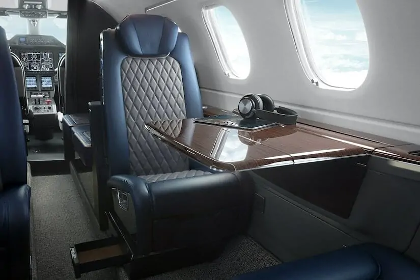 Embraer Phenom 300E interior seat with table out and headphones on table