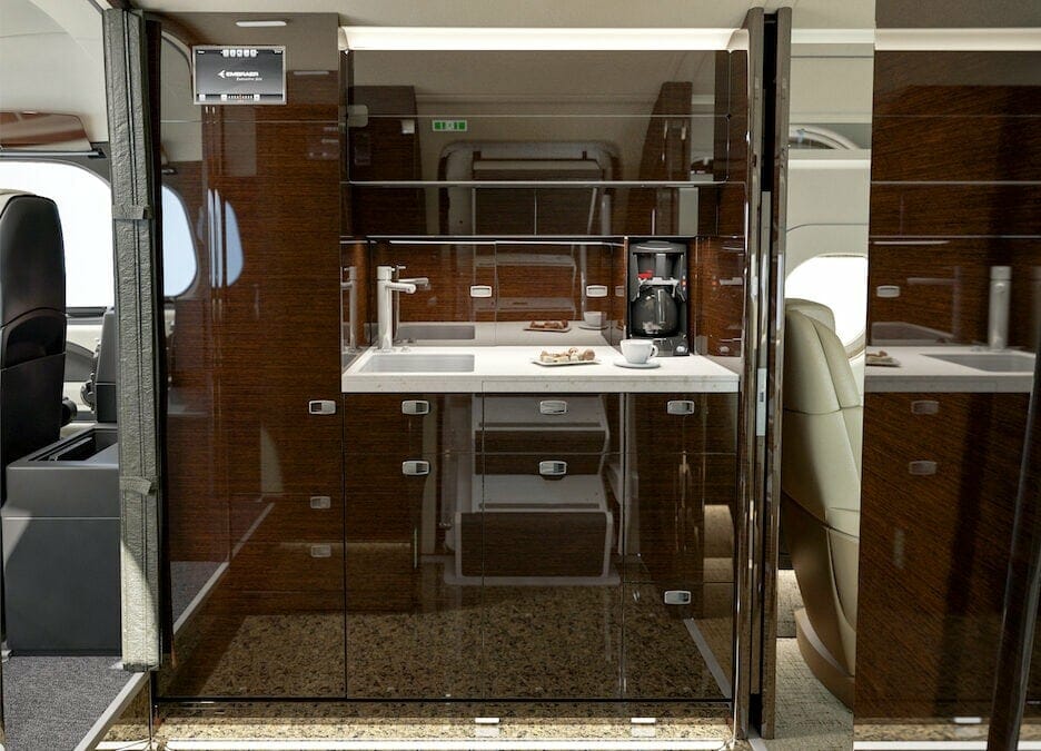 Embraer Legacy 500 galley with coffee maker, brown cabinets from the view of the entrance door