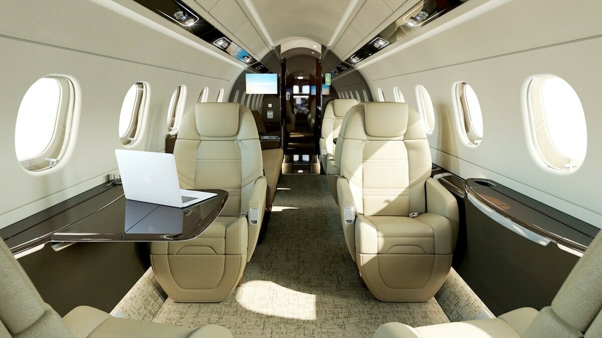 Embraer Legacy 500 binneruim met roomkleurige sitplekke en 'n divan wat na die agterkant van die vliegtuig kyk