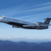 Embraer Legacy 650E Exterior view from below flying past mountains with a blue background
