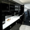 Embraer Legacy 650E galley with gloss piano black cabinets, white counter top, sink and cakes