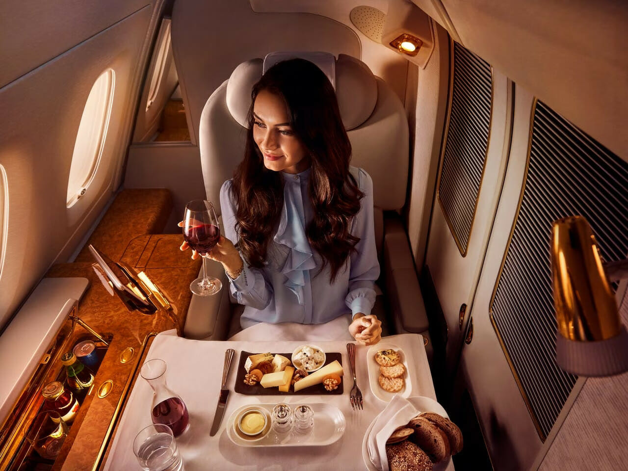 Woman sitting in first class drinking wine - private jet vs first class