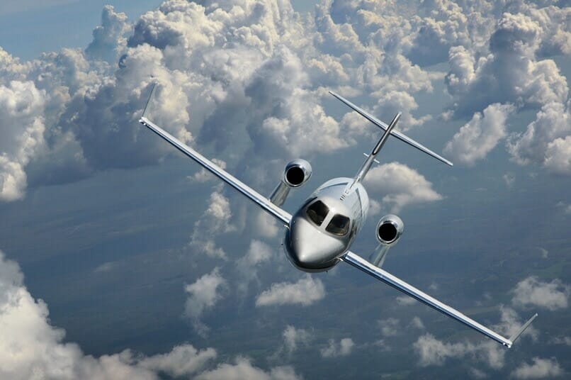 Външен въздушен изстрел на HondaJet, летящ през облаци в сребърна боя