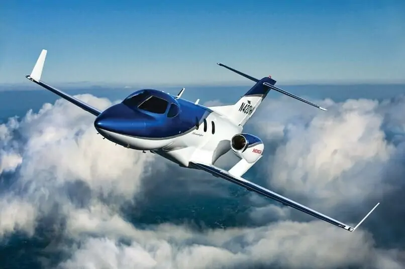 HondaJet Exterior in blue paint, aerial shot above the clouds banking left. Private jet from New York to Washington, D.C.