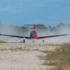 Pilatus PC-12 red landing on dirt runway