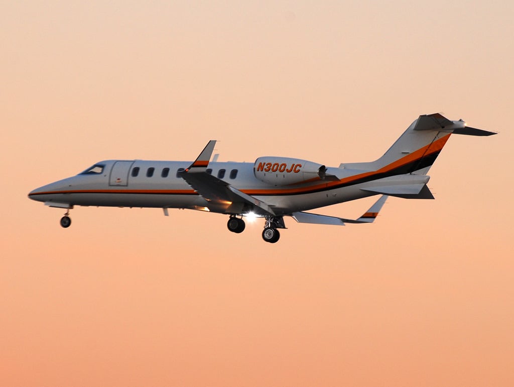 Bombardier Learjet 45 esterno N300JC con cielo arancione dietro e carrello di atterraggio esteso