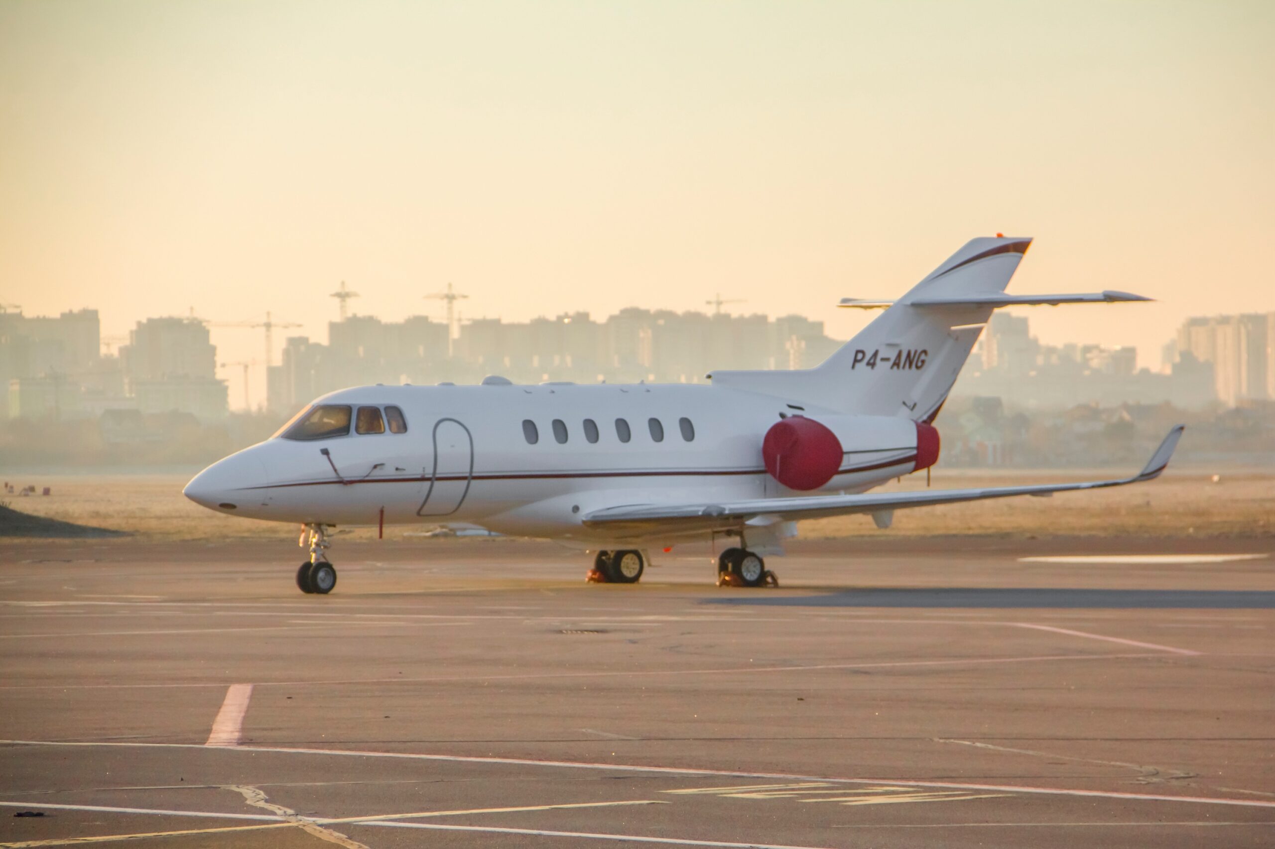 Hawker 900XP jet privato numero reg P4-ANG con coperchi motore sul piazzale dell'aeroporto all'alba