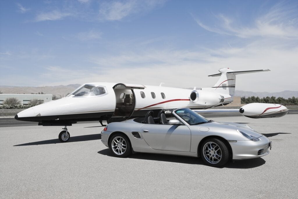 Vista di una Porsche Boxster e Learjet jet privato in aeroporto