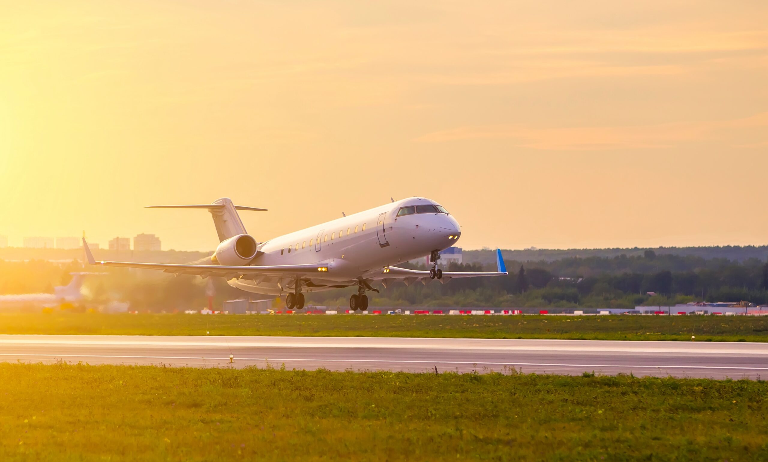 Bombardier jet privado despegando contra el fondo de las nubes del atardecer y la luz dorada del sol