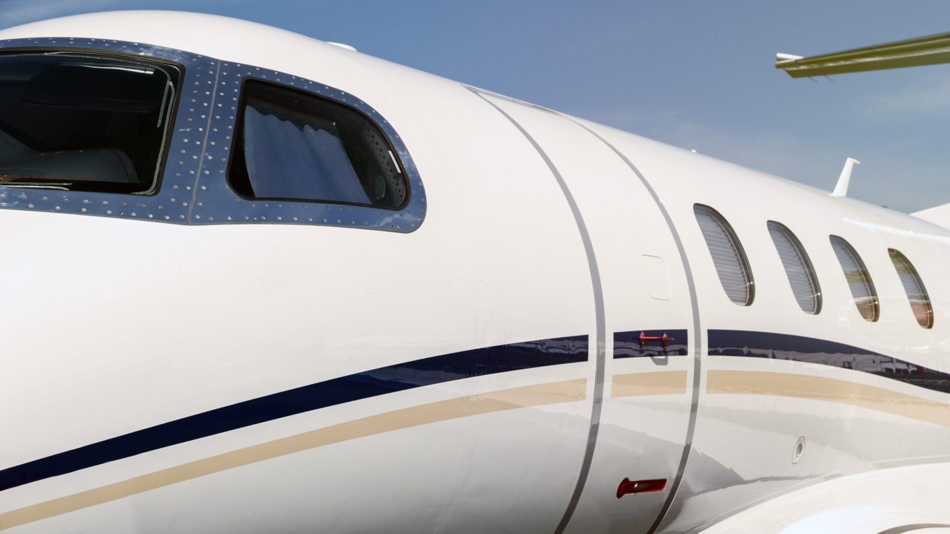 Primo piano della porta d'ingresso di un moderno aereo jet aziendale bianco e dei finestrini della cabina di pilotaggio.